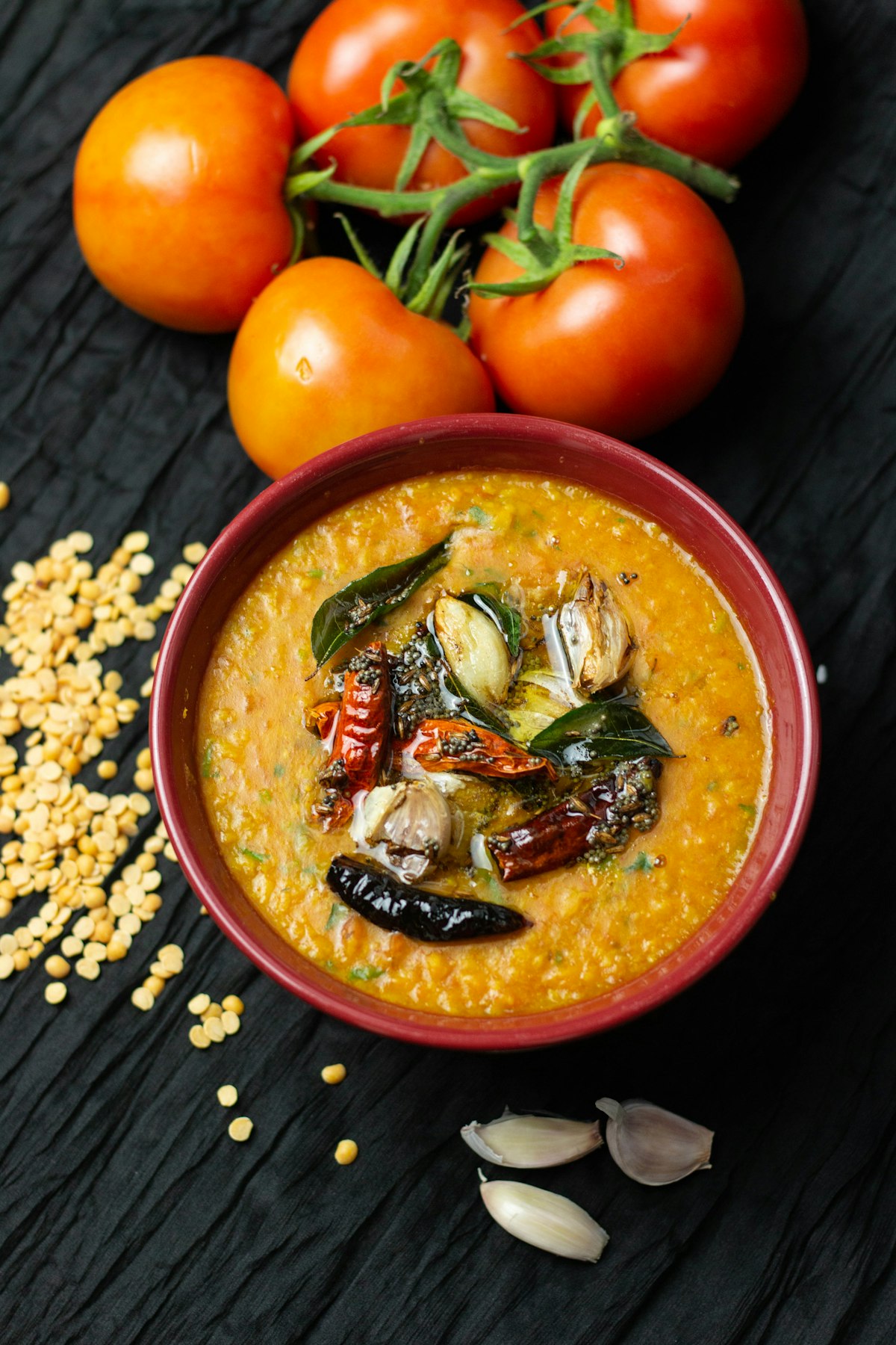 Dal tadka in a red bowl, finished with whole dried chillies, curry leaves and browned garlic
