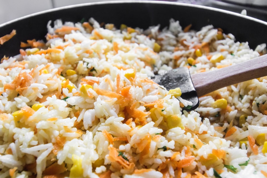 Fried rice with carrot, corn and herbs being turned in a black pan