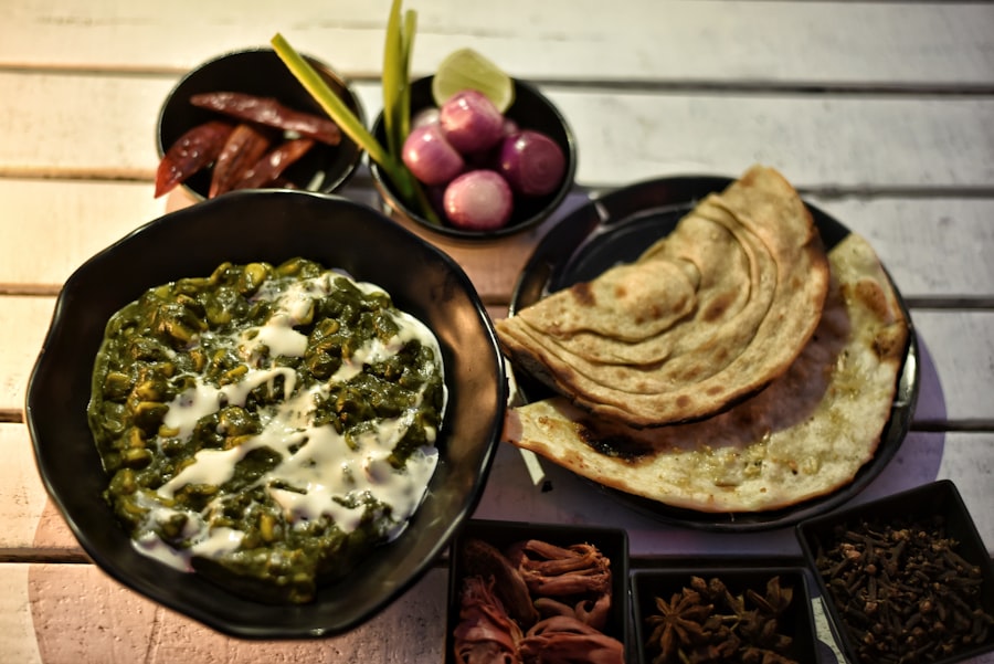 Stacked paratha beside a bowl of palak paneer, sliced red onion and lime